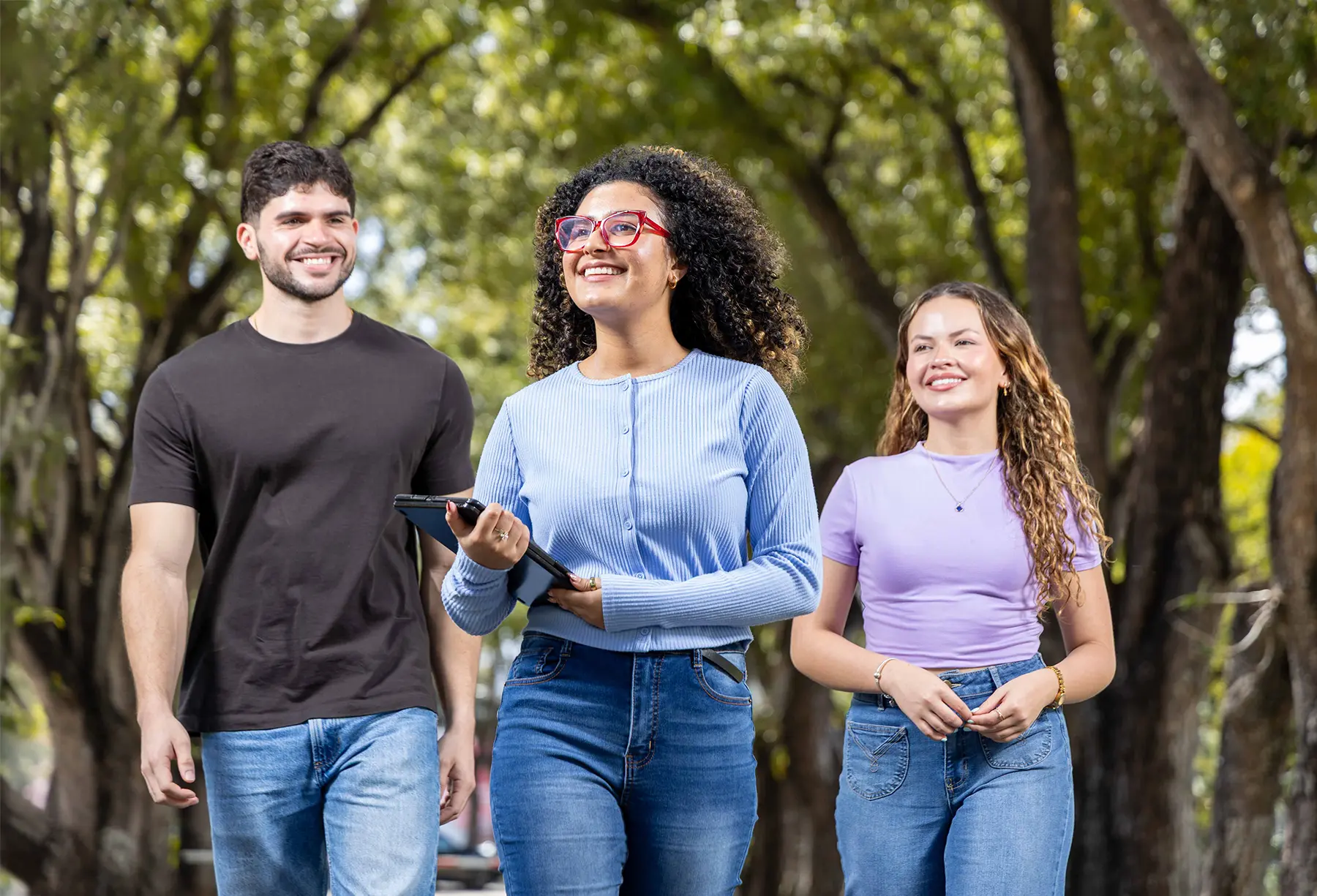 Tres jóvenes caminando sonrientes en el en el campus de la Universidad del Sagrado Corazón