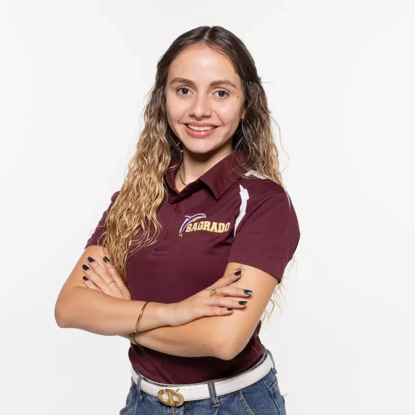 Mujer joven sonriendo con polo granate y brazos cruzados