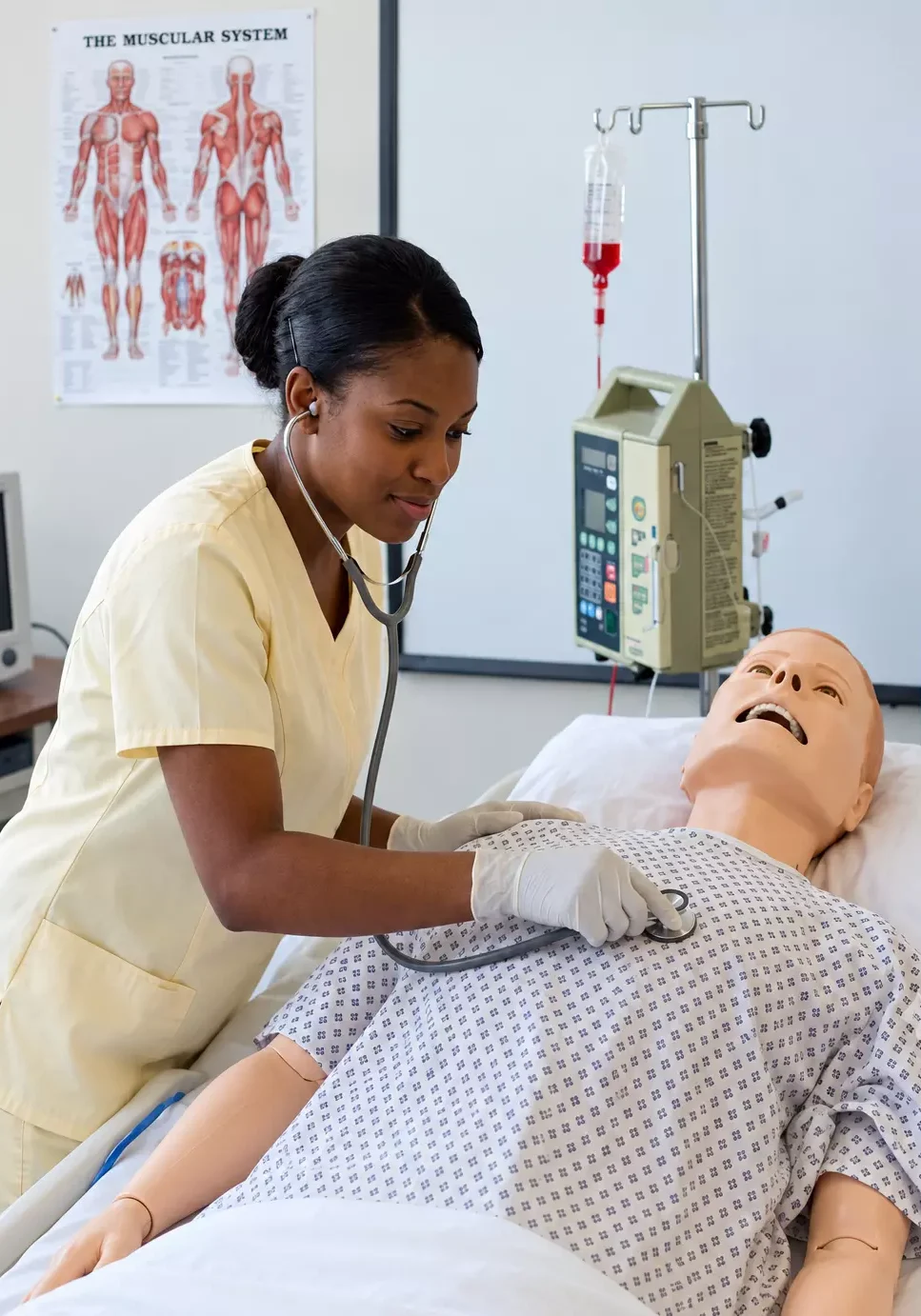 Enfermera ausculta a maniquí médico en una cama hospitalaria