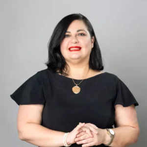 Mujer sonriente con vestido negro sobre fondo gris