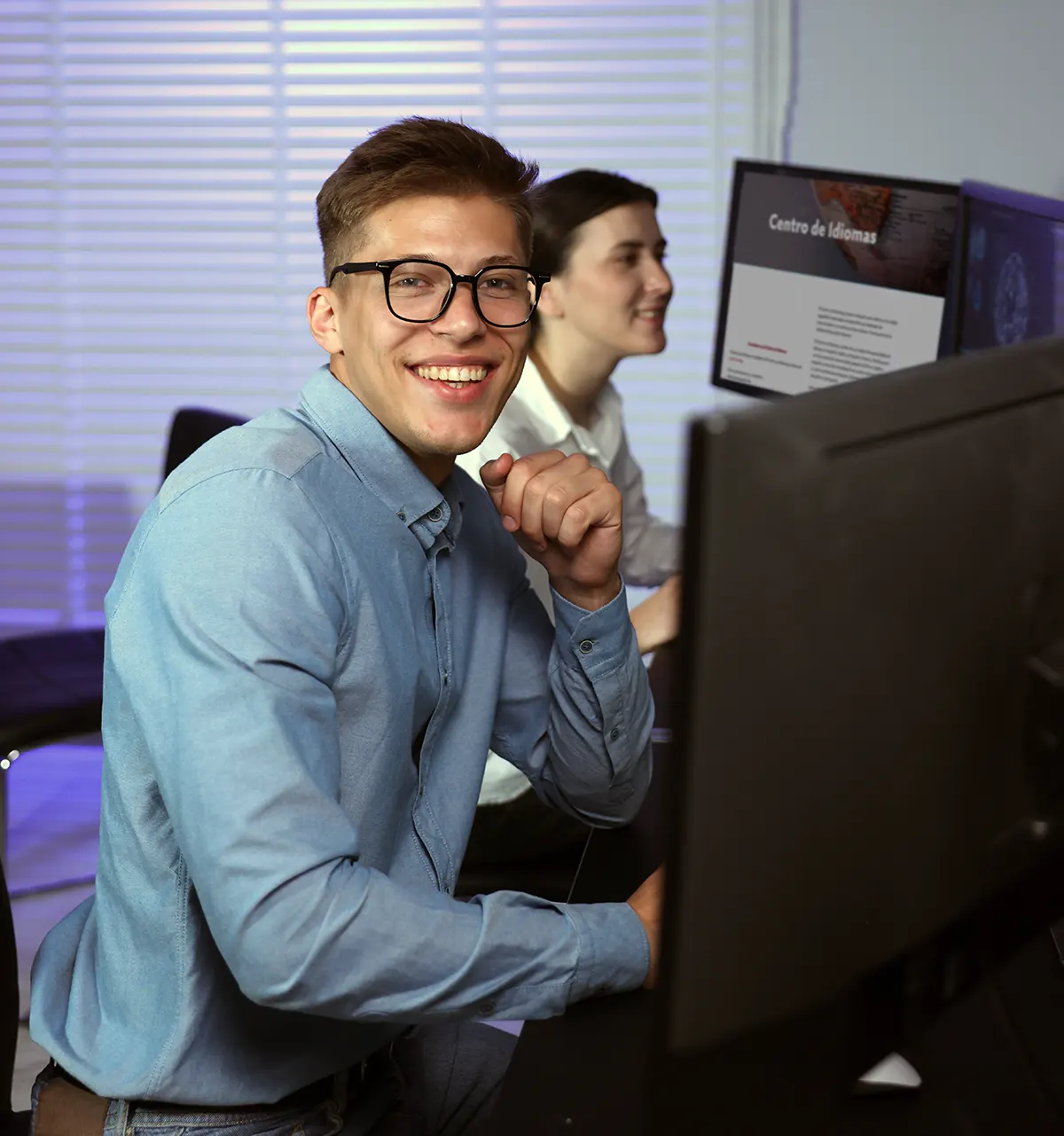 Dos profesionales trabajando ante ordenadores en una oficina