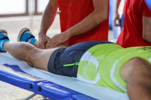 Fisioterapeuta masajeando pierna de deportista en camilla