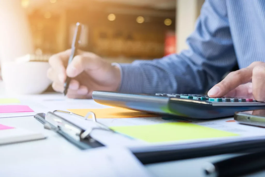 Person calculates and records financial data on a desk