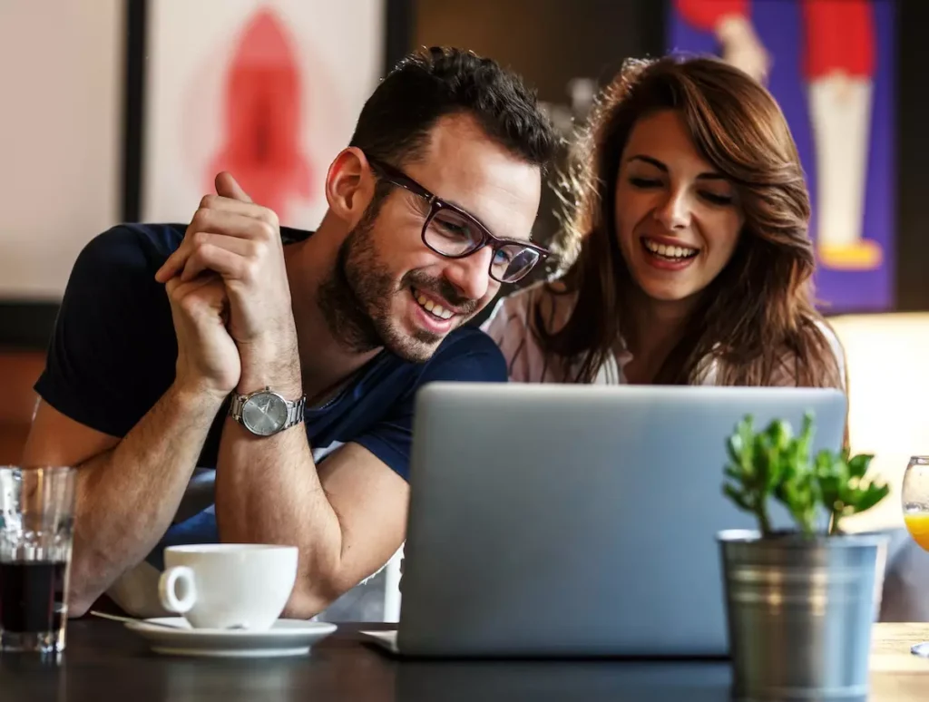Pareja sonriente mirando portátil en una cafetería