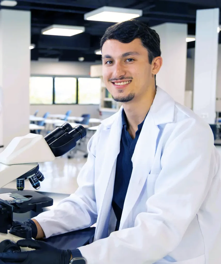 Científico sonriente usando microscopio en laboratorio moderno