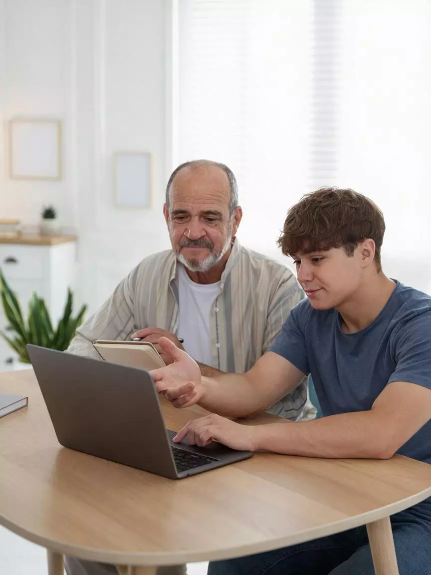 Abuelo y nieto usando un portátil en casa