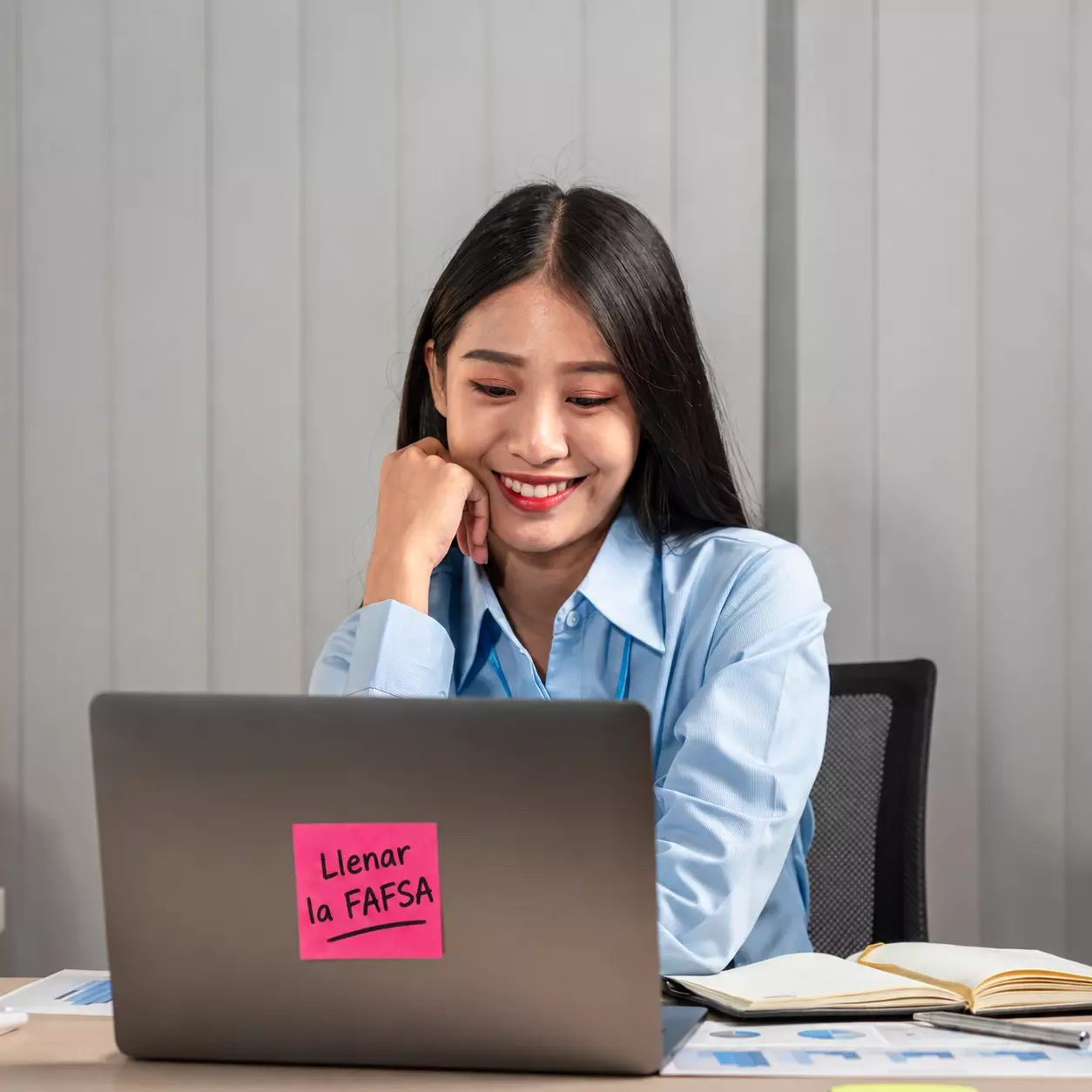 Mujer sonriente completa la FAFSA en su portátil