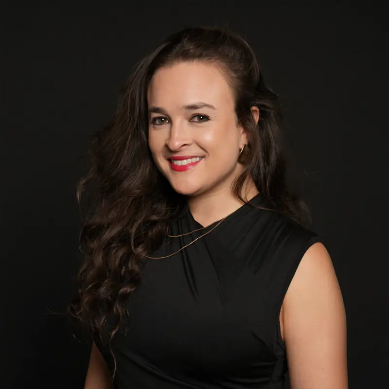 Mujer sonriente con vestido negro sobre fondo oscuro