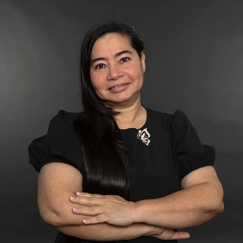 Mujer sonriente con brazos cruzados sobre fondo gris