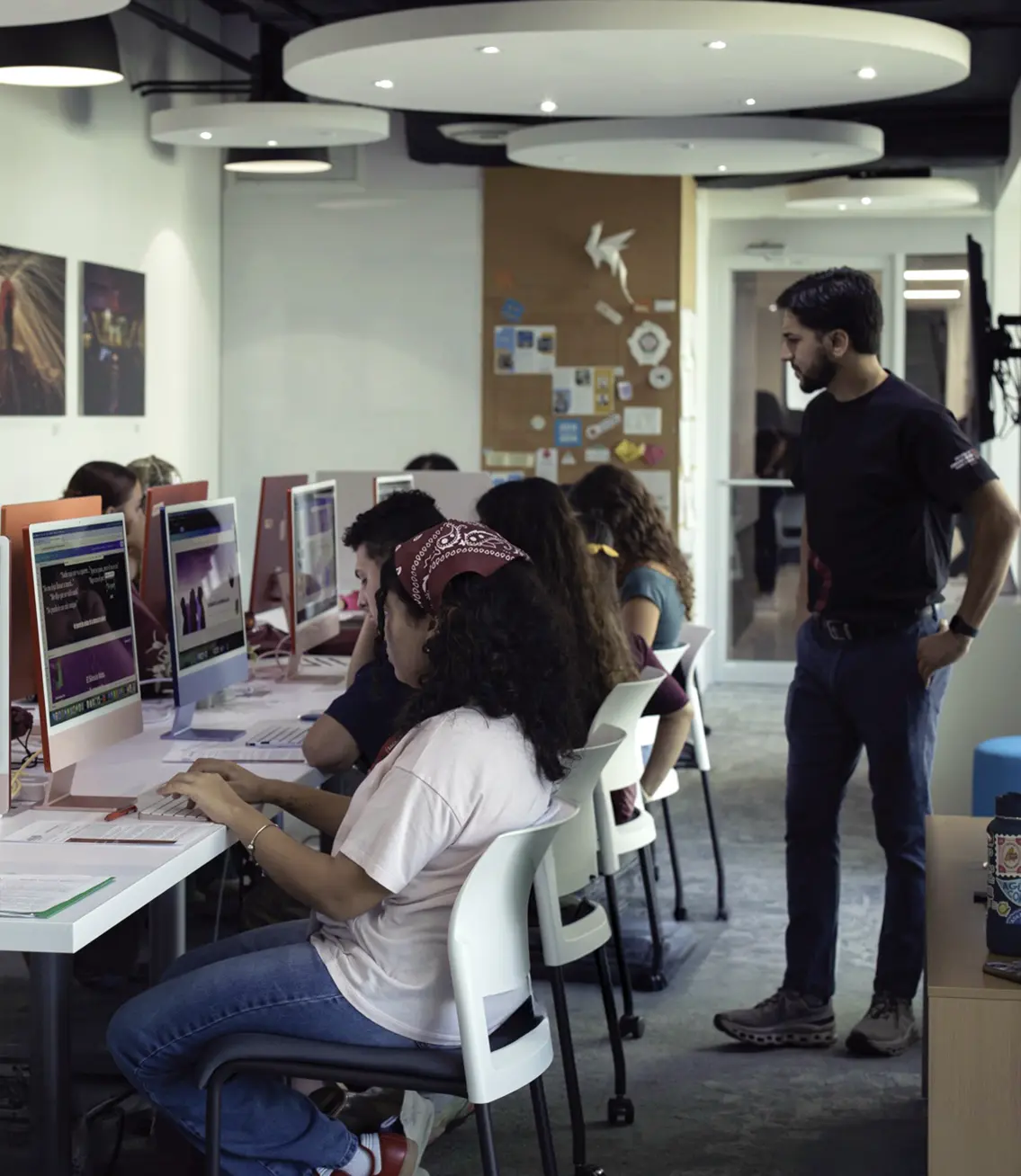 Estudiantes trabajando en ordenadores con profesor supervisando